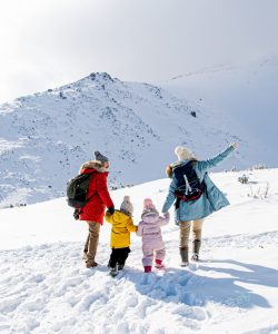 Rear view of happy family with two small children in winter nature, walking in the snow.